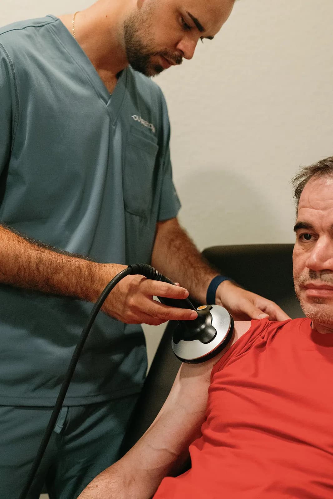 OutRecover clinician applying focused shockwave therapy to a client's shoulder